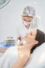 Obraz na płótnie Canvas Doctor performing laser mole removal procedure in beauty center