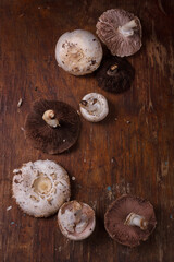 Fresh champignons on wooden table. Seasonal ogranic healthy food, ketogenic diet. Mushrooms on rustic background. Close up vertical shot, close up.
