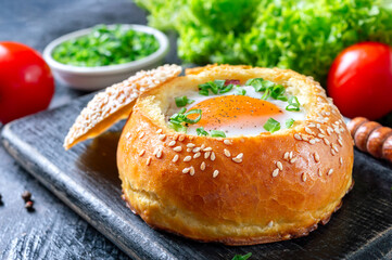 Egg baked in a bun with ham, cheese and herbs. French breakfast. Healthy eating concept
