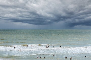 Sea beach before the storm. Thunderclouds are approaching the beach, rain in the distance. People...