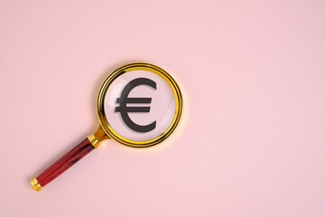 Euro symbol under magnifying glass, on pink background.