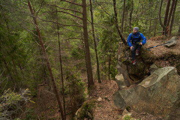 Obraz premium Male trekker sitting on forest crag during rest stop