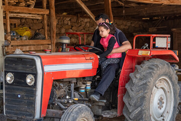 Closeup shot of little girl and young man inspecting tractor with selective focus.