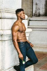 African American Man seeking love in New York. Shirtless, half naked, waring blue jeans, a young, strong, sexy guy standing by column on street, holding white rose, waiting. filtered effect..