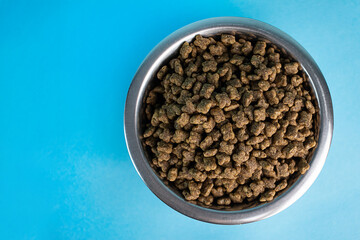 Top view bowl with dry dog food for small breed dogs on a blue background, space for text, balanced pet food