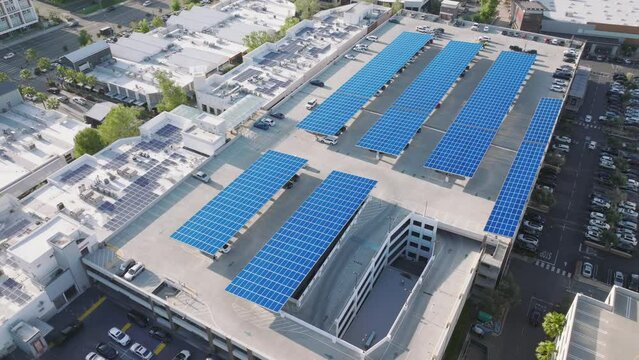 Solar PV solution installed at the rooftop of a parking lot as seen from above. Aerial view of downtown garage with sustainable energy panels. High quality 4k footage