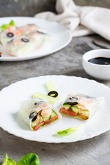 Spring roll cut in half in rice paper with seafood and vegetables on a plate. Vertical view