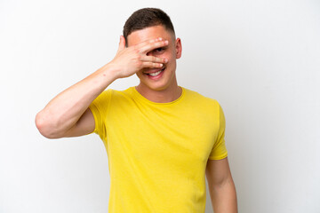 Young brazilian man isolated on white background covering eyes by hands and smiling