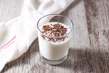 Yogurt or kefir with flax seeds in the glass on the brown wooden background.