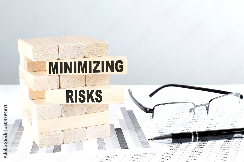 Poster minimizing risks is written on wooden blocks on a chart background