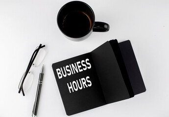 BUSINESS HOURS written text in small black notebook with coffee , pen and glasess on white...