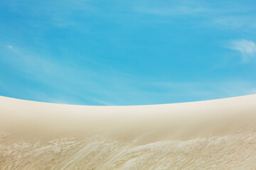 White sand dune and blue sky on background