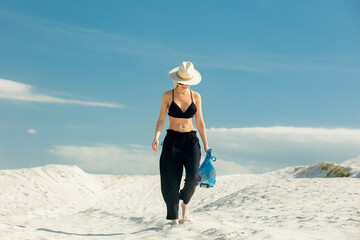 Woman walking on white  sand dune in desert in summer