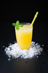 Glass of fresh orange juice with ice on a black background with a place for inscription