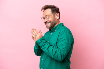 Middle age caucasian man isolated on pink background scheming something