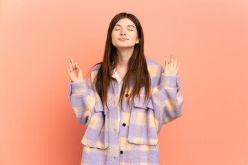 Young Ukrainian girl isolated on pink background in zen pose