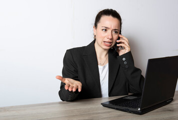 ragazza arrabbiata  che lavora al computer  mentre telefona col cellulare