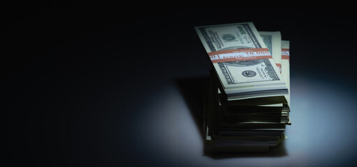 Stacks of US Dollar bill money against dark background. Copy space.