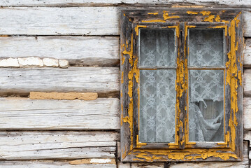 Window in an old wooden house. A decaying rural old wooden house. Wall of a country house with a window. The structure of the old wood.