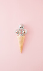 Ice cream cone with four shiny disco balls on pink background. Flat lay. Minimal concept.