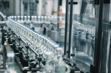 Production line transports empty glass bottles for alcohol