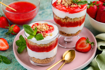 Crispy creamy strawberry trifle in a glasses. Delicious summer dessert of shortbread crumbs, yogurt quark cream and strawberries. Selective focus