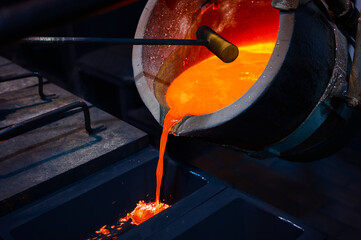 Pouring silver into graphite casting form in dark workshop