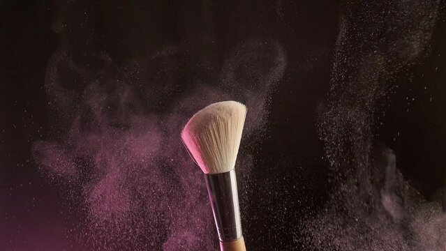 Close up selective focus shot of shimmer powder being shaken off makeup brush