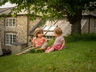 Little siblings girl and boy are eating fresh watermelon on a sunny day on her summer holidays at the countryside in a cottage in England