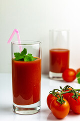 Glass of tomato juice on a white background. The background is blurry.