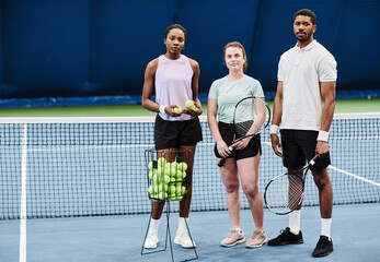 Full length portrait of young people standing at tennis court and all looking at camera, copy space - Powered by Adobe