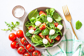 Green salad with fresh leaves, tomatoes and mozzarella. Top view, copy space.