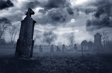 Old creepy graveyard on stormy winter day with full moon in black and white