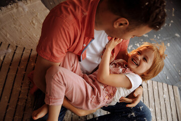 Joyful girl in pink and dad playing with feathers