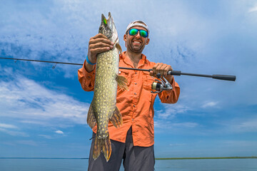 Pike fishing. Successful fisherman hold muskie fish