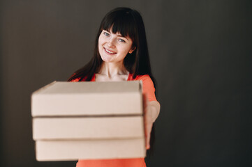 A young girl holds pizza boxes in her hands and sincerely smiles looking up.
