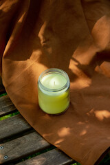 Aroma candle on blrown cloth and wooden chair in garden