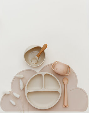 Set of tableware and silicone bibs. Baby accessories. Kids nutrition and feeding concept. Top view, flat lay