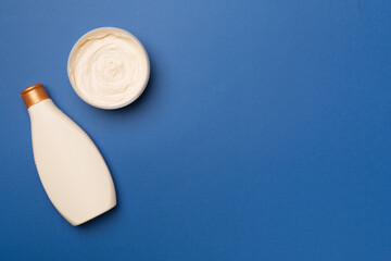 Shower gel and body cream on color background, top view