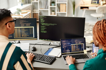 High angle of two IT developers using computers while reviewing code in office
