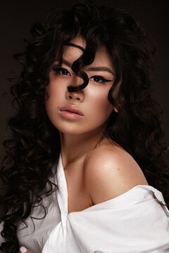 Portrait of a beautiful asian woman in a white shirt, with makeup and curls. Beauty face.