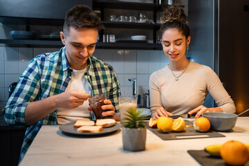 Fototapeta na wymiar Young couple caucasian man and woman husband and wife or boyfriend and girlfriend brother and sister students preparing breakfast in the kitchen at home real people copy space daily morning routine