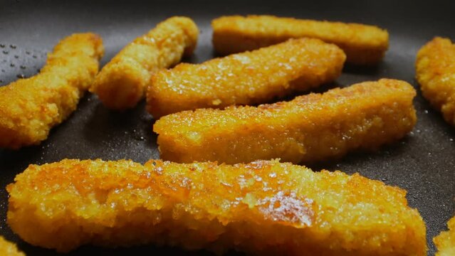 Chicken nuggets frying in a pan.