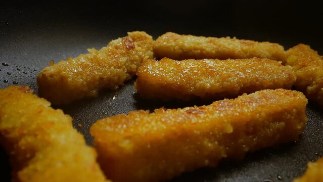 Chicken nuggets frying in a pan.