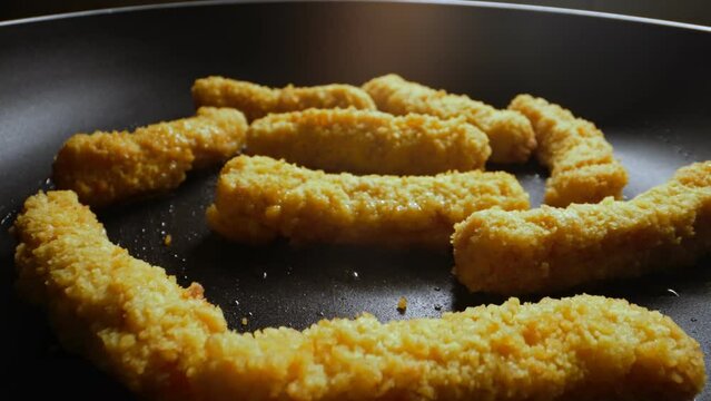 Chicken nuggets frying in a pan.