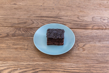 Portion of brownie with death by chocolate on blue plate and wooden table