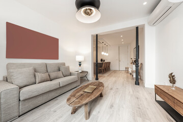 living room with two-seater sofa upholstered in light fabric, oblong coffee table in raw wood and...