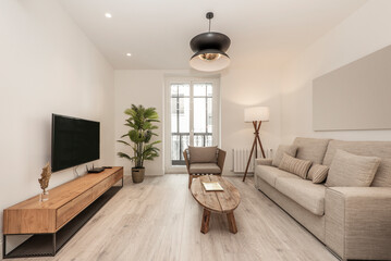 living room with two-seater sofa upholstered in light fabric, oblong raw wood coffee table, light...