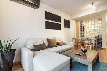 Fototapeta premium Living room with a gray leather sofa with a divan, a wooden side coffee table, a metal dining table and a skylight in the wall with glass paves