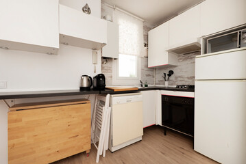 Fototapeta premium Kitchen with white cabinets, black countertop, light hardwood floors and wooden folding dining table